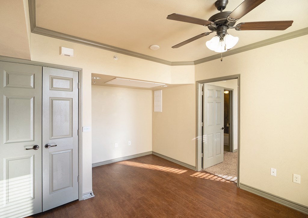 a empty living room with a ceiling fan and a door to a hallway