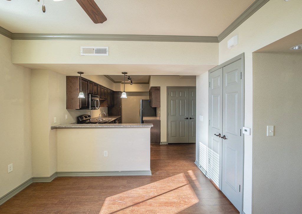 an empty living room with a kitchen and a door