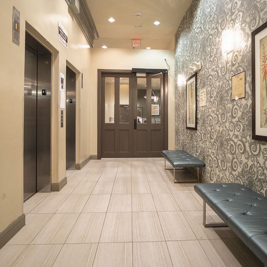 the lobby of a building with two doors and a bench