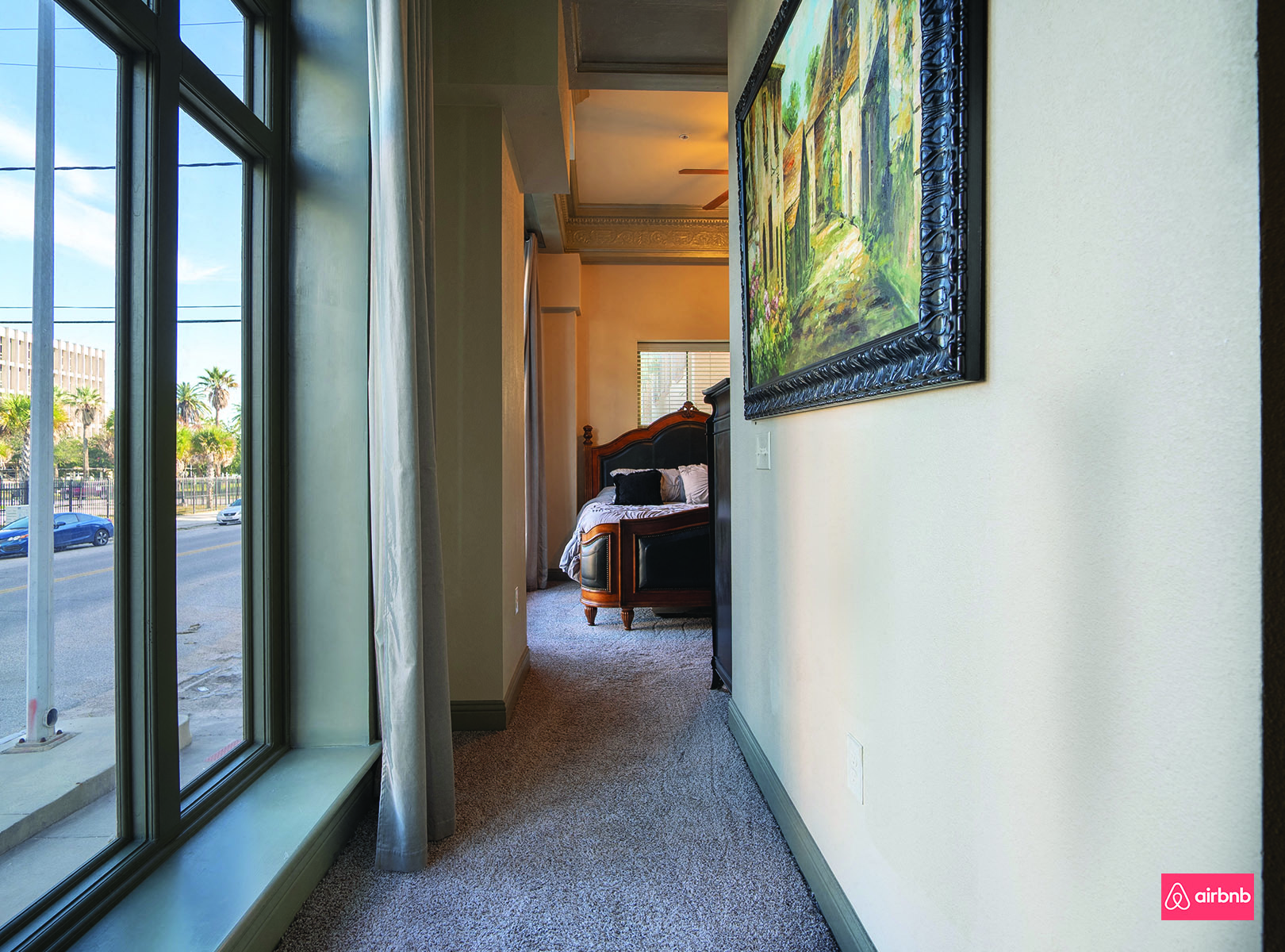 a hallway with large windows and a painting on the wall
