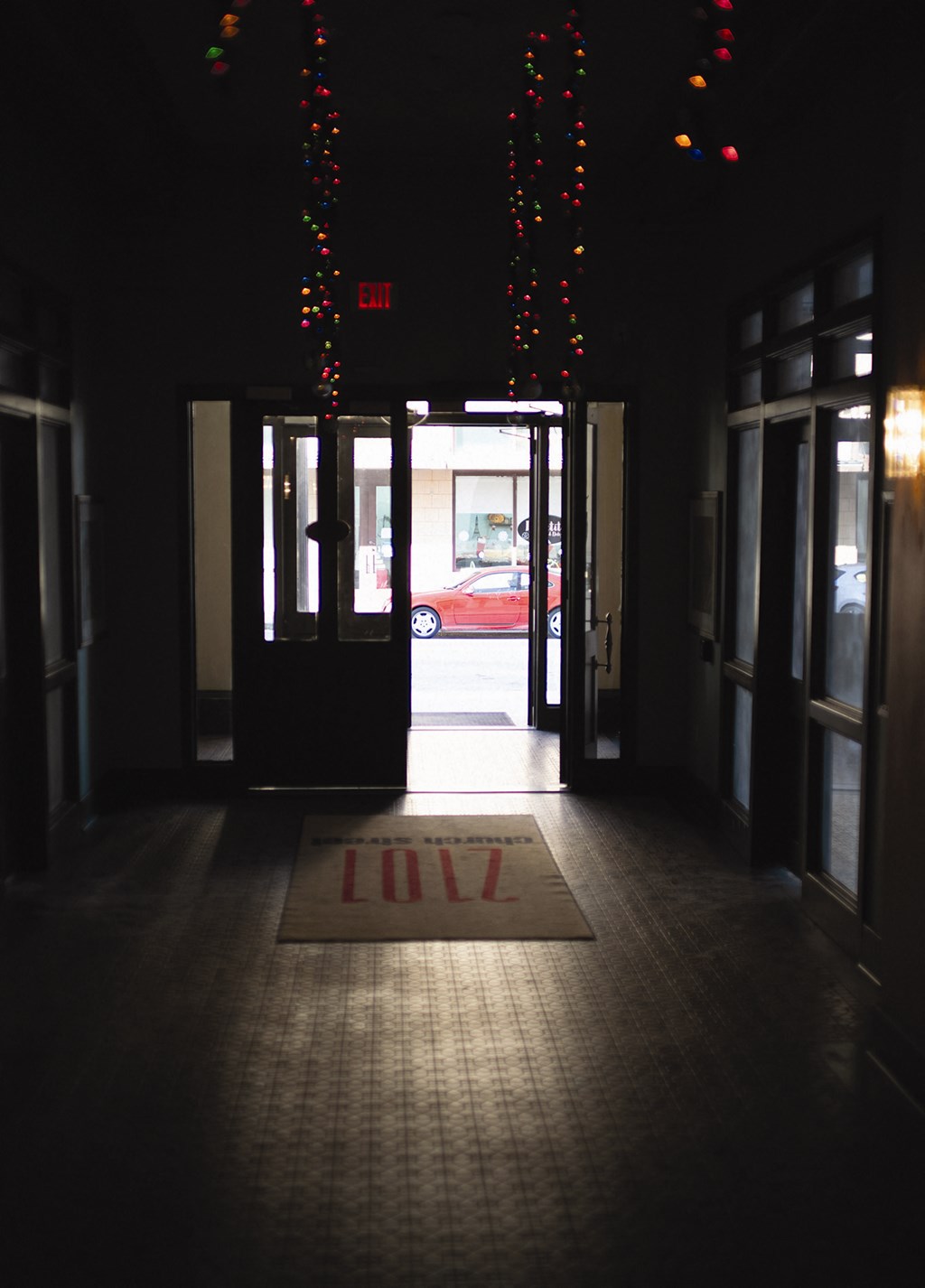 the entrance to a hotel lobby at night with a rug and lights on the floor