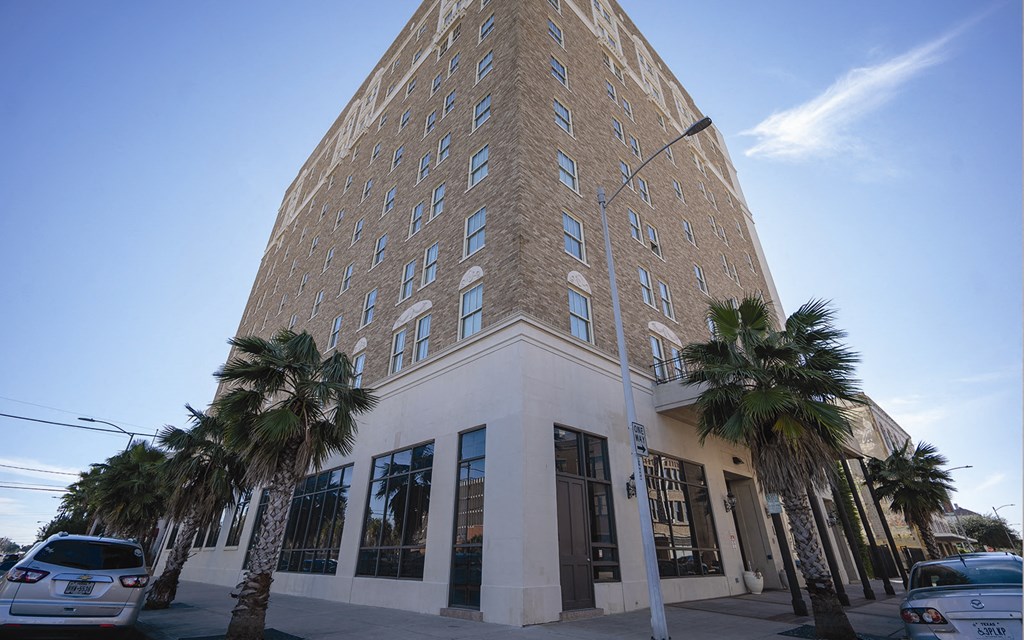 a tall brick building with palm trees in front of it