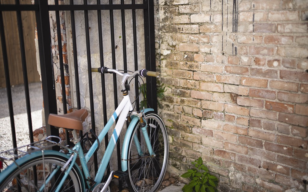 A green bike is leaning against a brick wall.