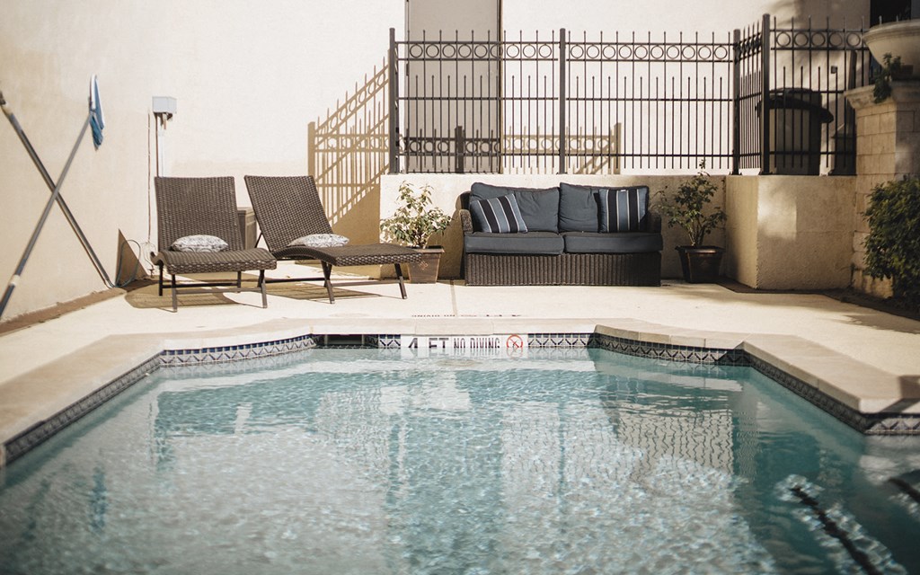 a swimming pool with two chairs and a couch next to it