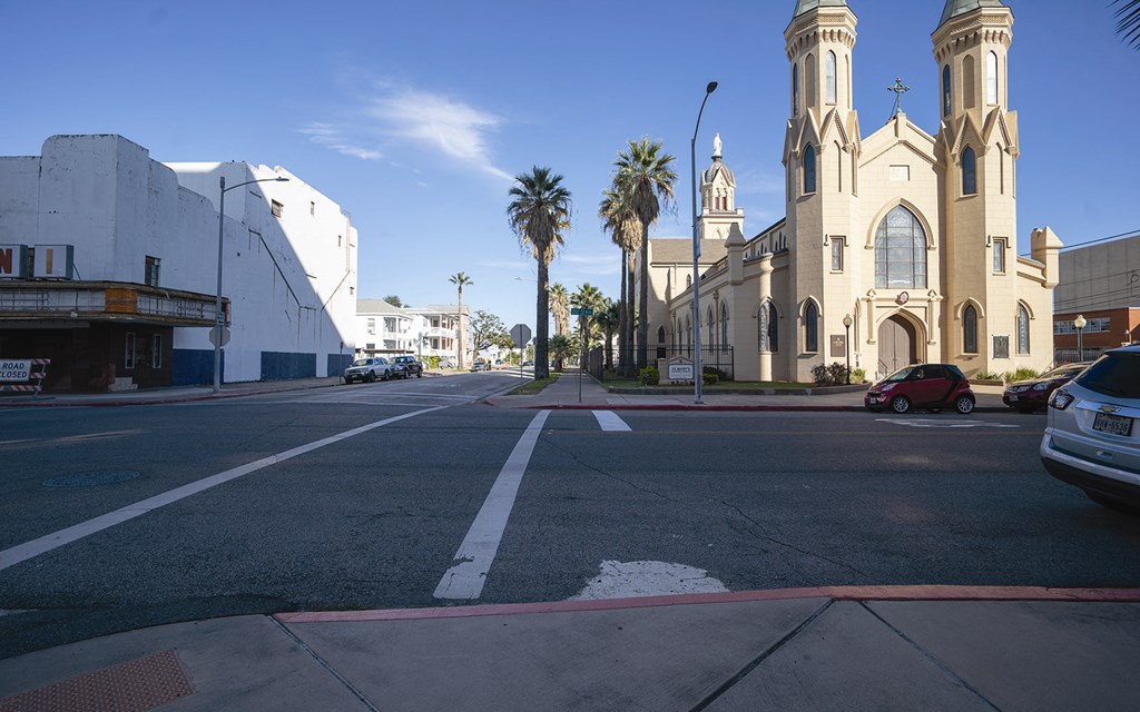 a city street with palm trees and a church on the corner