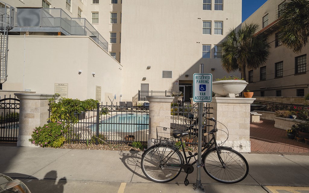 a bicycle parked next to a parking meter in front of a fence