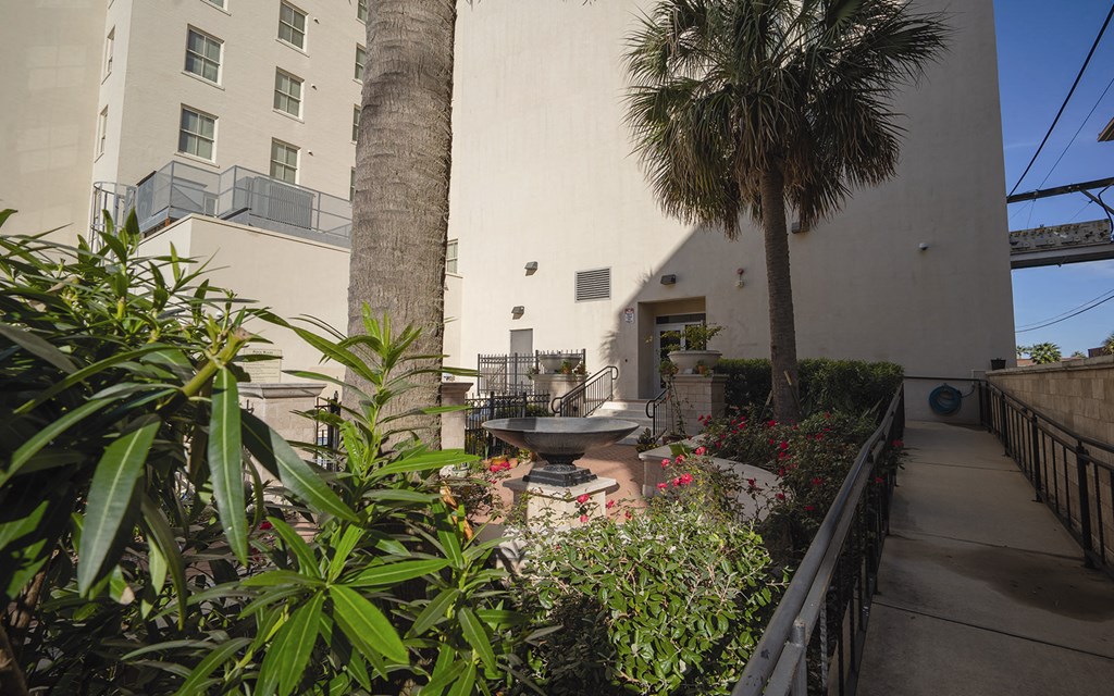 a courtyard with plants and a fountain in front of a building