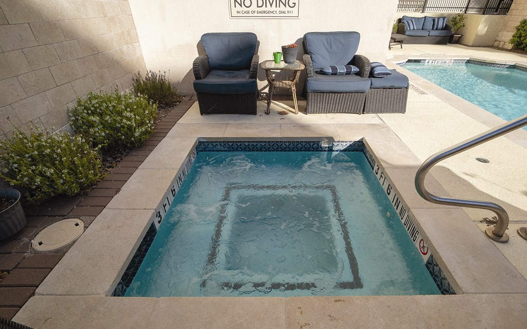 a hot tub in a backyard with two chairs and a pool