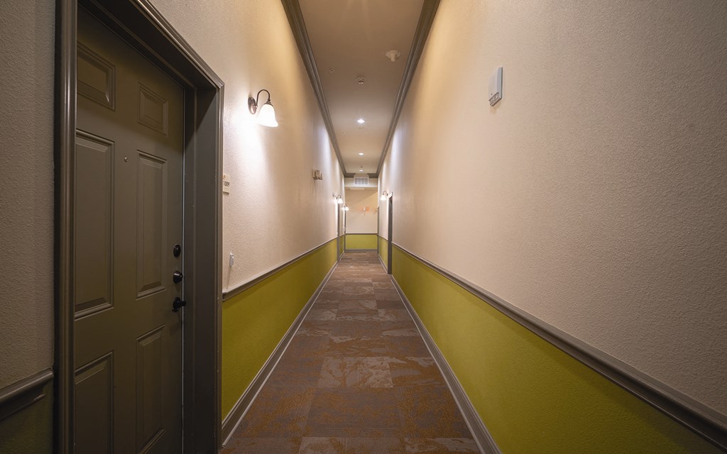 a long hallway with a brown and green floor and a door
