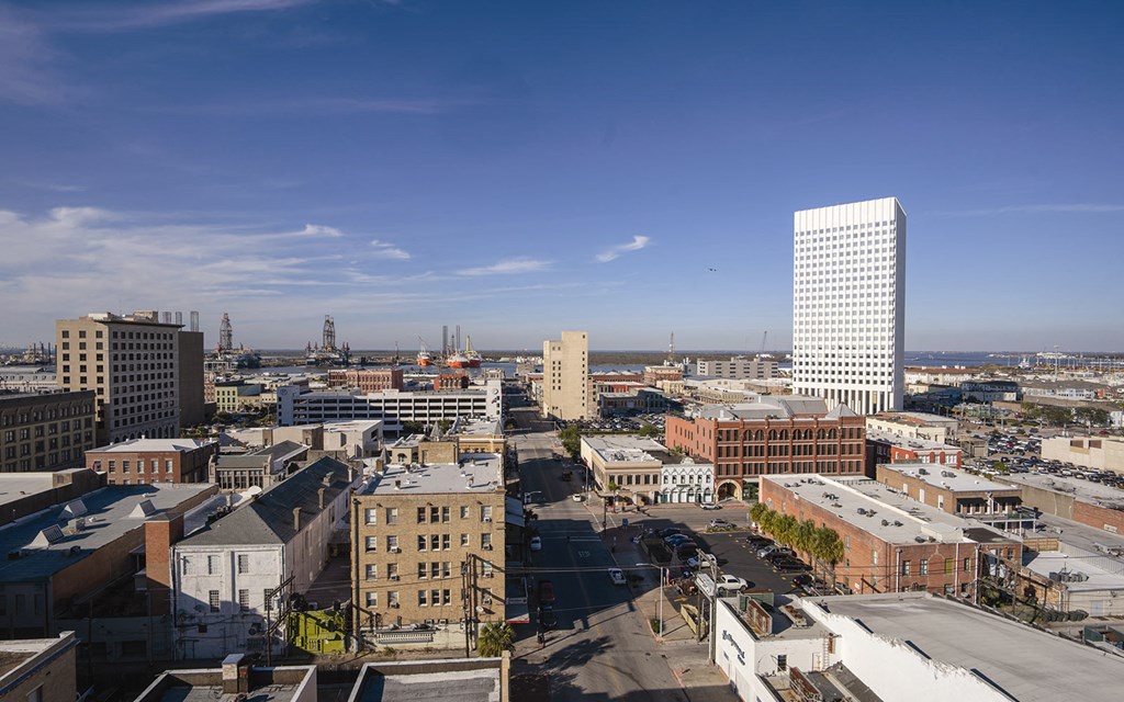 A cityscape with a variety of buildings, including a tall white building with a grid pattern.