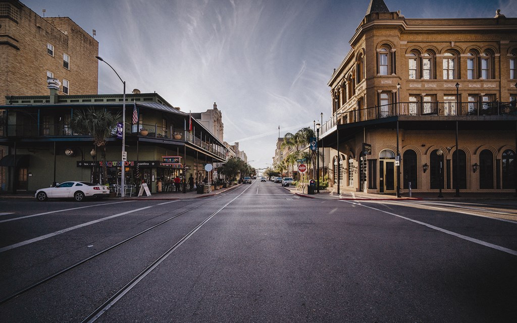 A street with buildings on either side and a car parked on the side of the road.