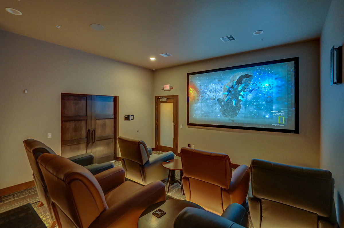 a living room with chairs and a large screen on the wall