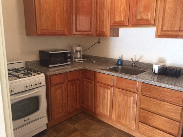 A kitchen with wooden cabinets and a white stove.