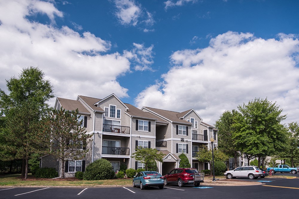 a three-story apartment building with parking lot.