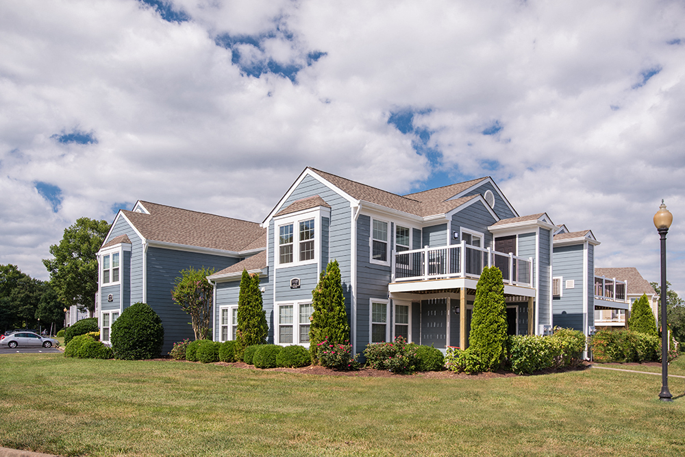 a blue apartment building exterior with large balcony and windows.