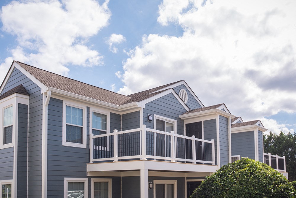 a blue apartment building exterior with large balcony and windows.