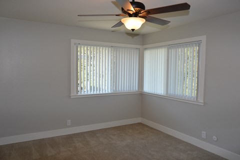 a bedroom with a ceiling fan and three windows
