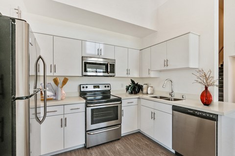 A modern kitchen with white cabinets and stainless steel appliances.