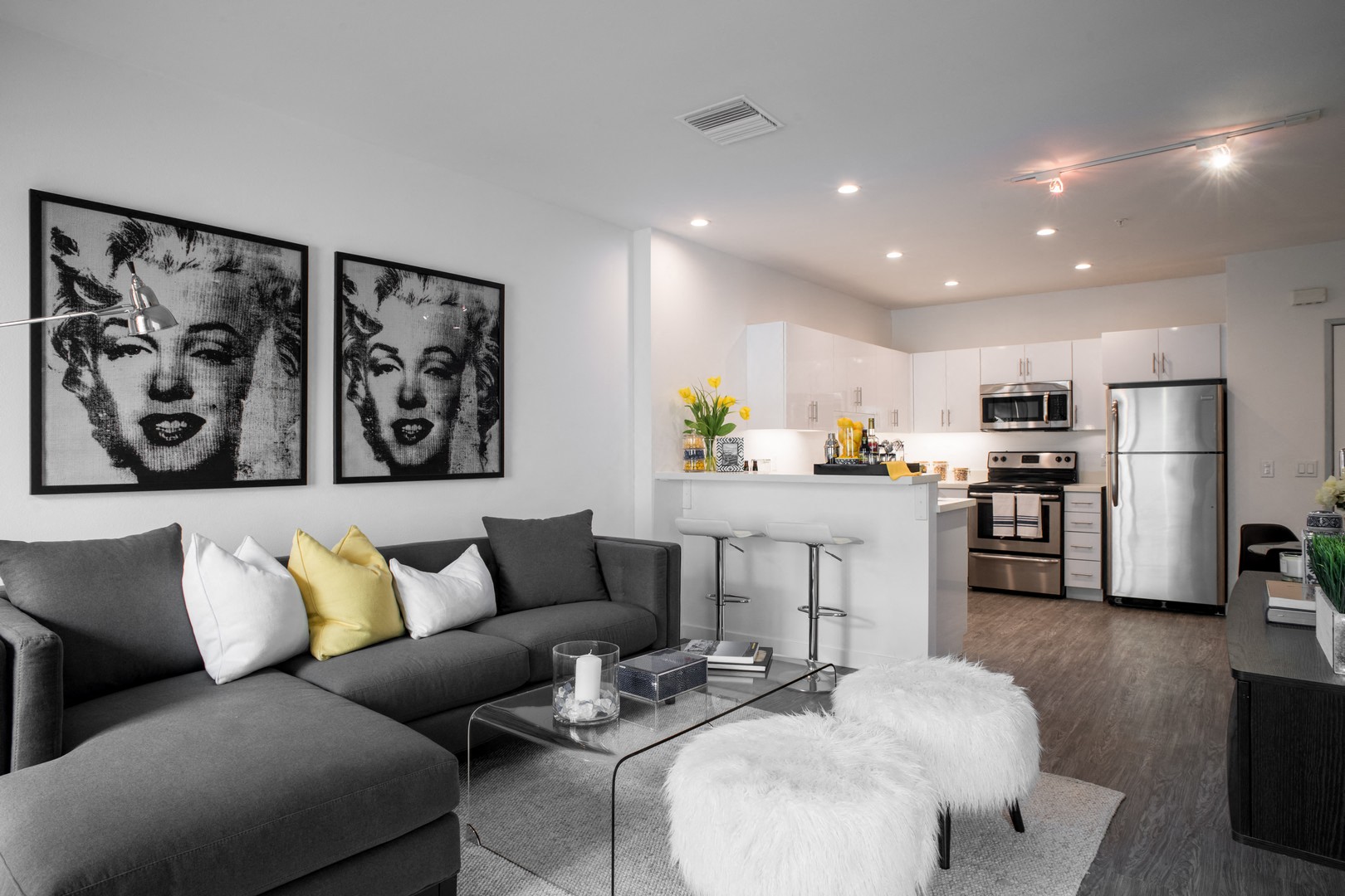 A modern living room with grey couches and a glass coffee table.