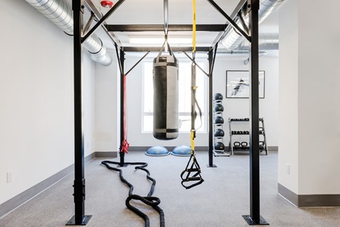 A gym with a punching bag, a rope and a bench.
