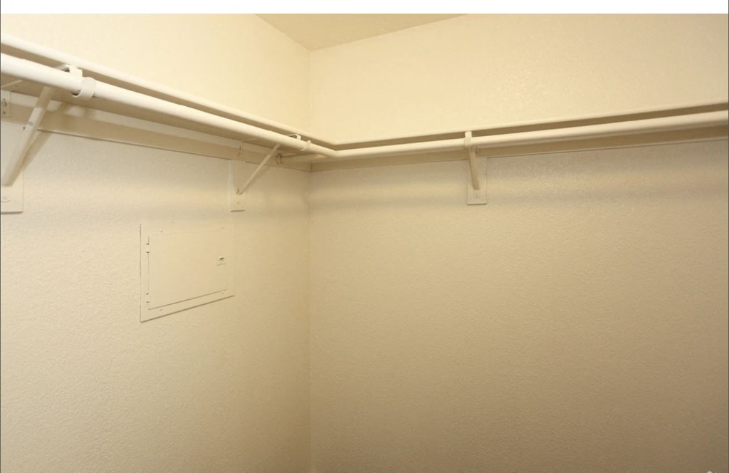 a walk in closet with a white wall and a white bracket on the wall