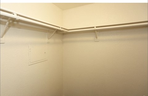 a walk in closet with a white wall and a white bracket on the wall