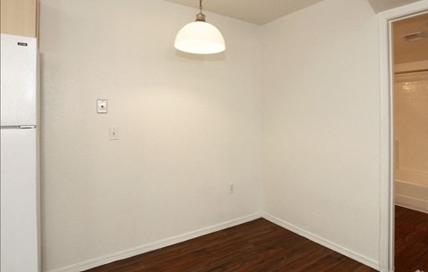 an empty room with a refrigerator and a lamp