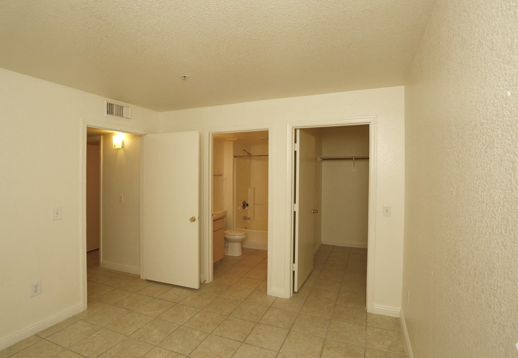 the living room of an apartment with a tiled floor and a bathroom