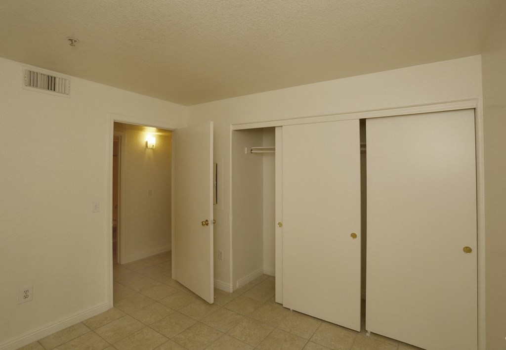 a bedroom with three closets and a tiled floor