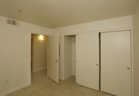 a bedroom with three closets and a tiled floor