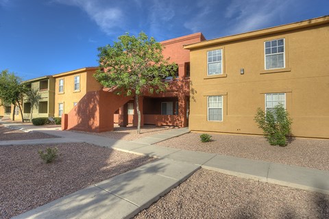 a yellow building with a tree and a sidewalk in front of it