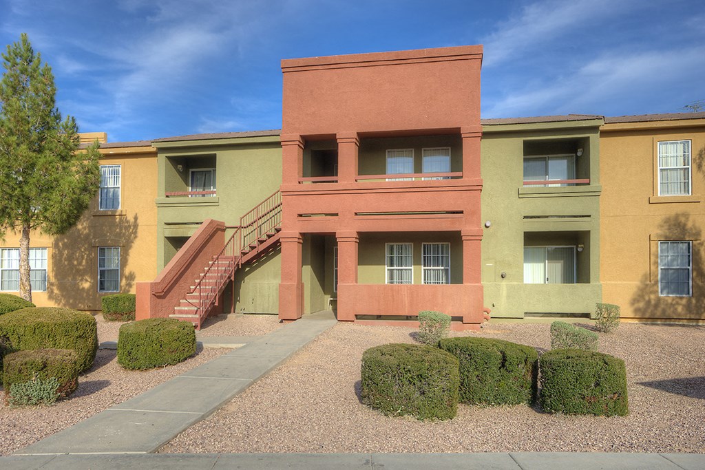 a building with stairs and hedges in front of it