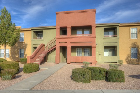 a building with stairs and hedges in front of it