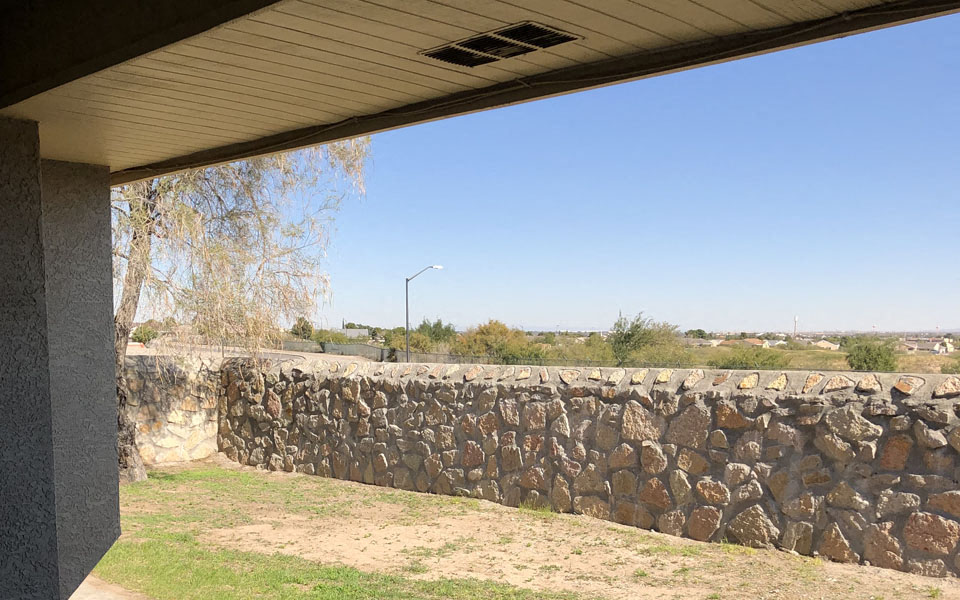 a stone wall next to a building under a roof