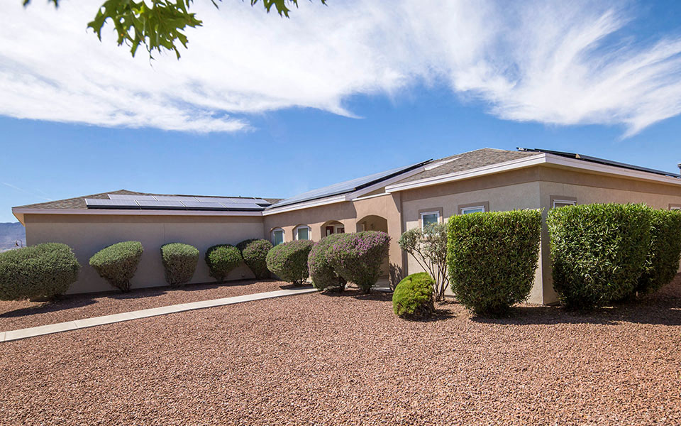 a house with a driveway and hedges in front of it