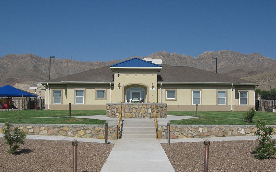a large yellow house with a stone wall in front of it