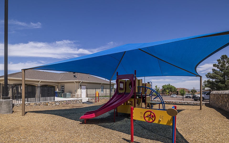 a playground with a swing set and a blue canopy