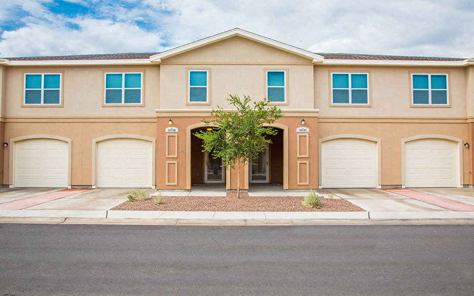 a house with three garage doors and a tree in front of it