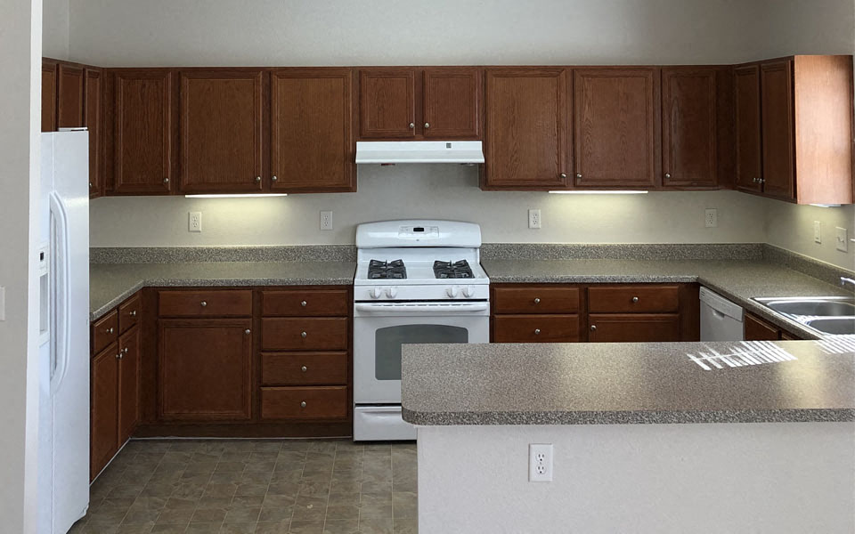 an empty kitchen with a stove and a refrigerator