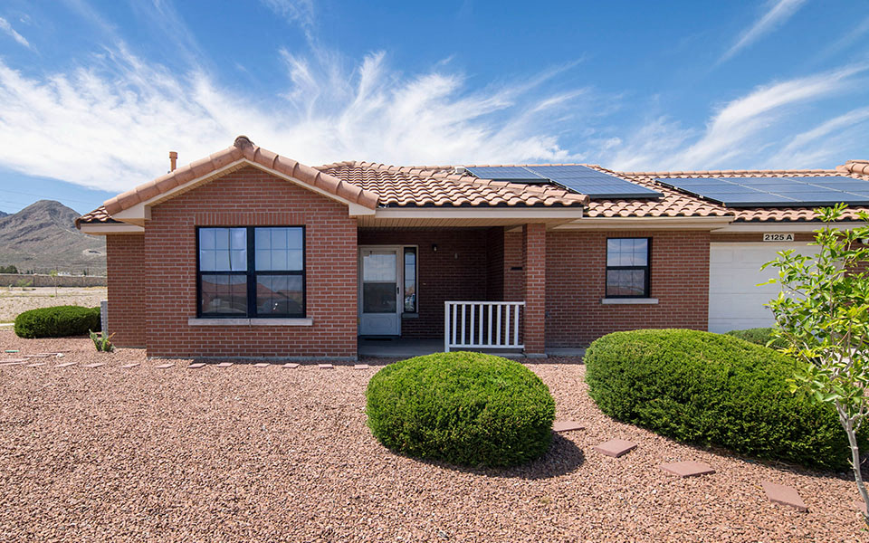a small brick house with solar panels on the roof