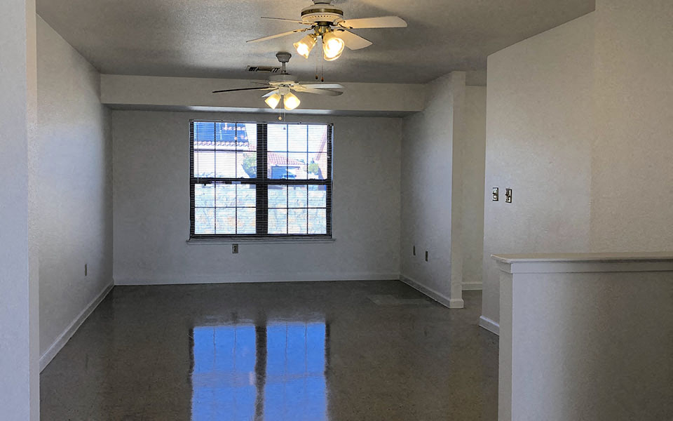 an empty living room with a ceiling fan and a window
