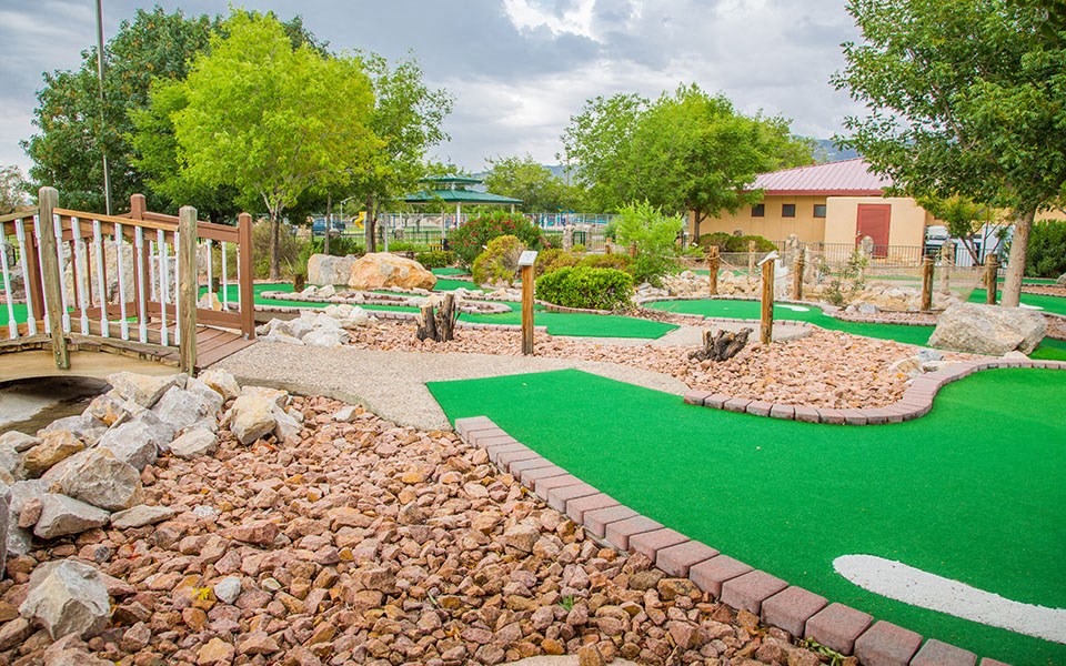 a mini golf course in a park with a bridge and rocks