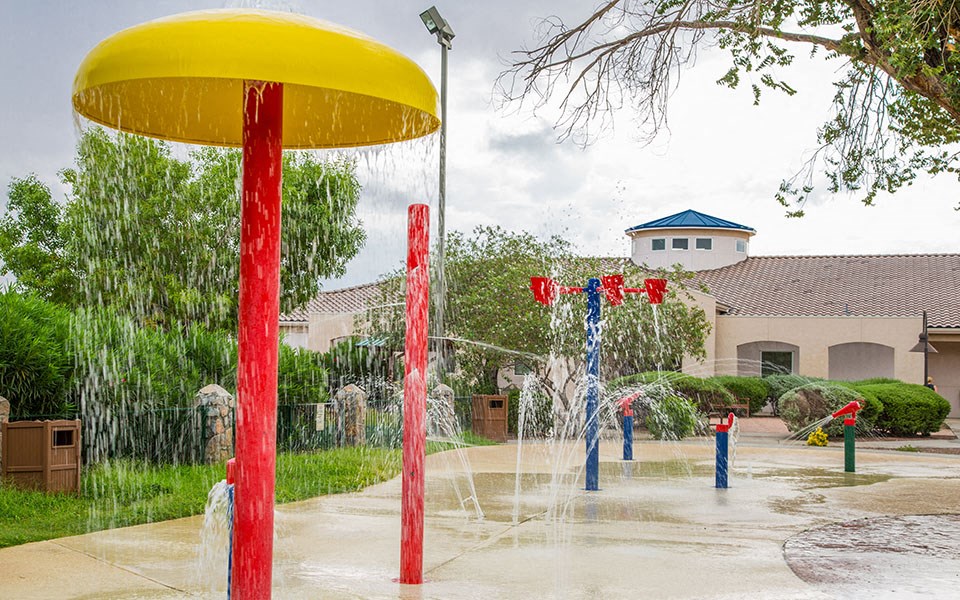 a water park with a yellow umbrella and red and blue fountains