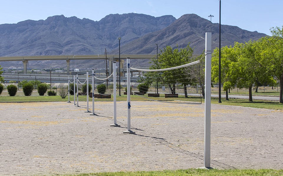 a row of volleyball nets on a dirt field with mountains in the background