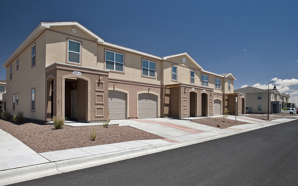 a street view of an apartment building with two garage doors