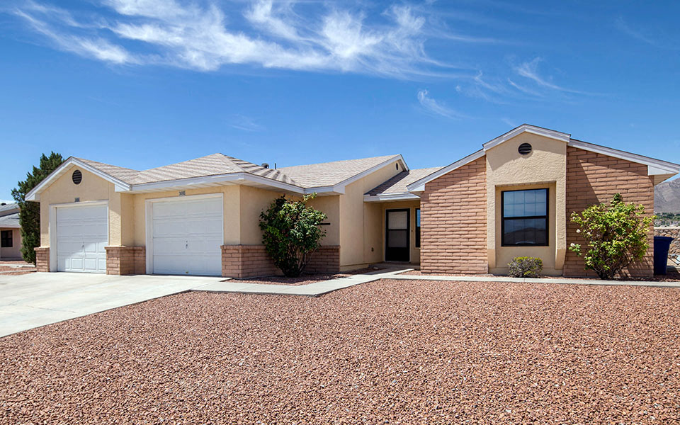 a house with two garage doors and a gravel driveway