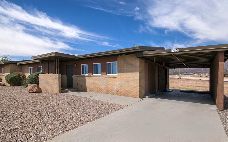 a brick house with a driveway and a blue sky