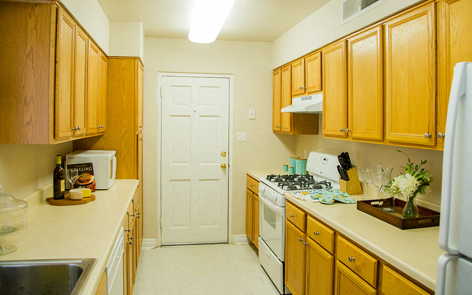a kitchen with wood cabinets and white appliances and a white door