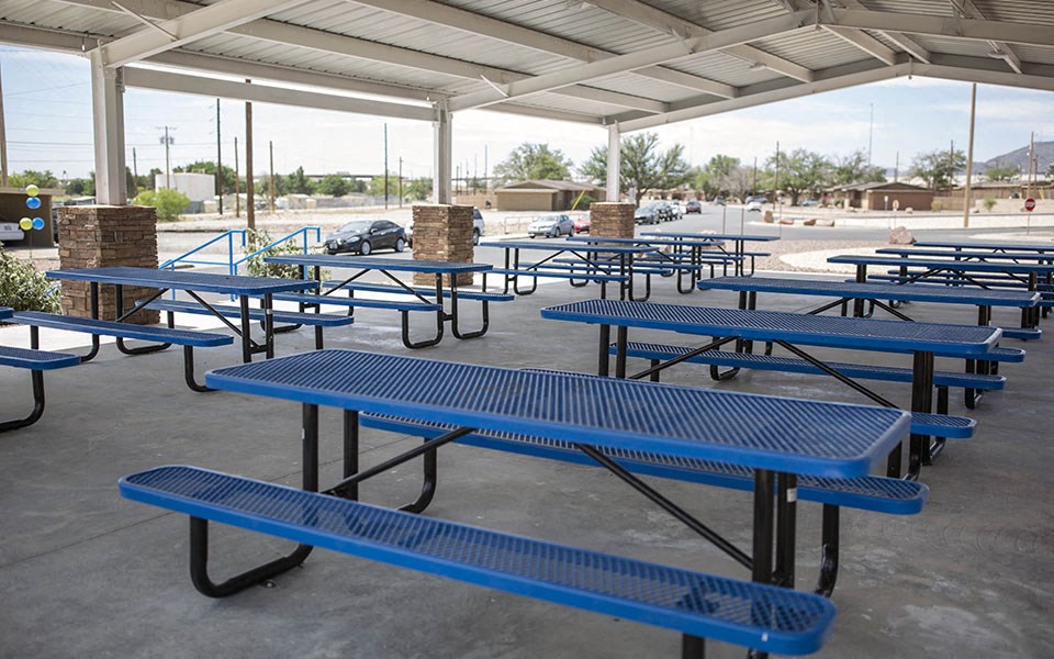 a group of blue picnic tables and benches in a park