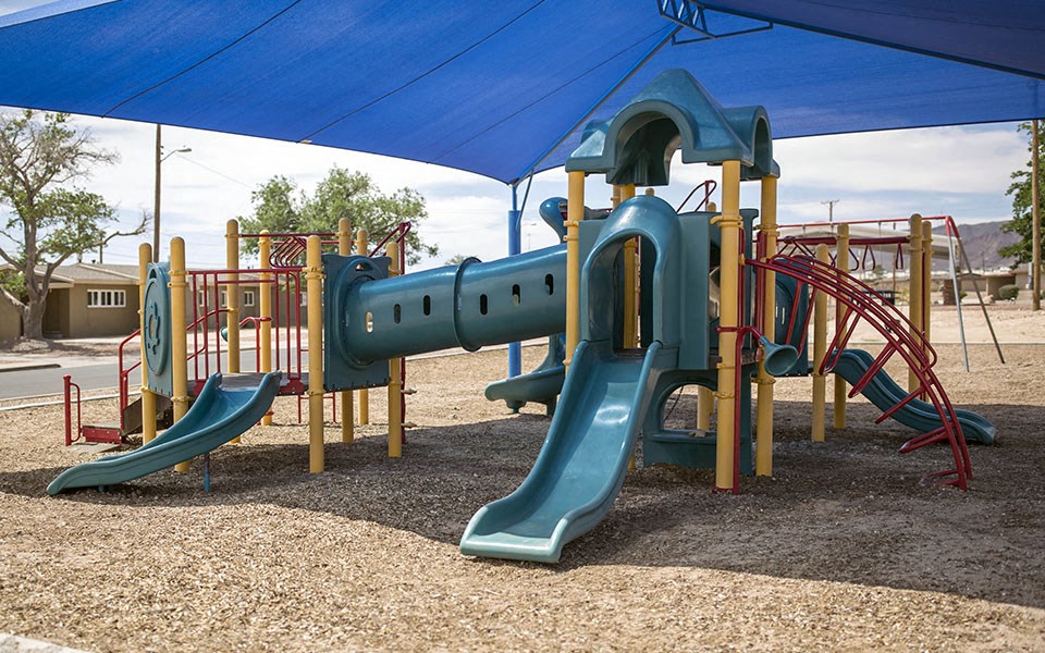 a playground with slides and a blue canopy